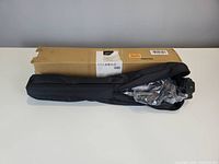 Cardboard box and black carry bag containing tripod