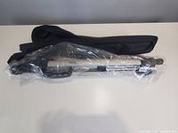 tripod in plastic wrap alongside carry bag