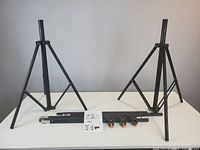 Two assembled tripod stands, crossbar sections, clamps and instructions displayed