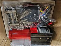 Winch in box showing red motor, steel cable, control box and wiring