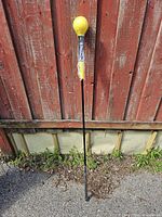 Full view of golf swing trainer leaning against fence