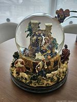 Full view of snow globe showing nativity inside globe and exterior figures on resin base