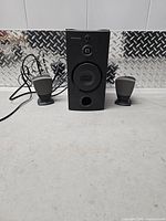 Front view of subwoofer flanked by both satellite speakers showing overall condition