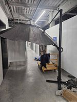 Umbrella open showing offset design, cross base, and weight plates nearby