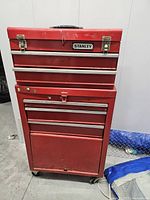 Front view of red Stanley rolling tool chest showing drawers, latches and logo
