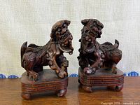 Pair of carved wood foo dogs on bases, frontal view