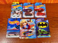 Six Hot Wheels cars on cards laid out on table