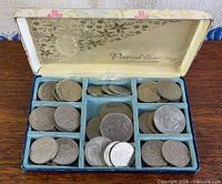 Partitioned box filled with stacks of silver-tone coins