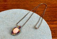 Full view of sterling silver necklace with pendant showing pink cabochon and multicoloured halo