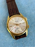 Close view of dial showing Invicta logo, 17 Jewels Incabloc text, dual crowns, gold-tone case and brown strap