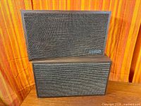 Front view of both speakers stacked showing grille and cabinets