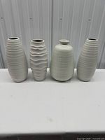 Group shot of four white textured ceramic vases