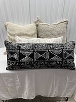 Front view showing three pillows: black/white lumbar, cream ribbed square, beige chevron square
