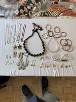 All items laid out on white cloth showing necklaces, bracelets, brooches, earrings