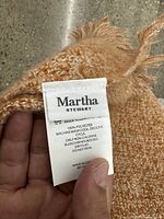Close-up of brand and care tag showing Martha Stewart, 100% polyester, made in China