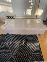 Overall view of clear plastic wheeled storage bin with lid closed