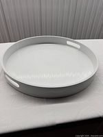 Top angled view of round white serving tray showing handles and glossy finish