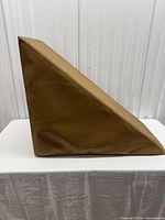 Side view showing right-angle triangular profile and tan faux leather surface