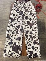 Full front view of animal print Adidas track pants laid flat