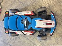 Top view of blue-white go-kart ride-on showing overall design, seat, steering wheel, wheels