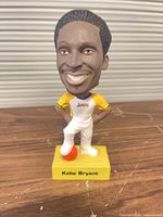 Front view of Kobe Bryant bobblehead on yellow base with basketball and printed name