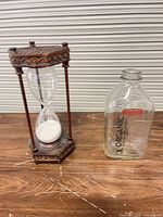 Hourglass timer and Straus glass milk bottle side by side on table