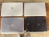Top view of all four laptops displaying lids and brand logos