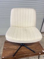 Front view of off-white fabric swivel chair on black metal base