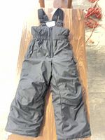 Full view of black toddler snow bib laid flat