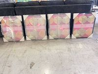 Four canvases leaning against sofa, three wrapped in bubble, one showing packaging corners