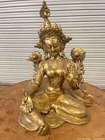 Front view of gilded brass seated Buddhist deity with lotus flowers