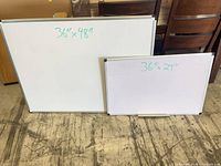 Two aluminum-framed whiteboards side by side displaying approximate dimensions