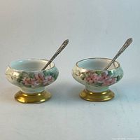 Two porcelain salt cellars with spoons inserted