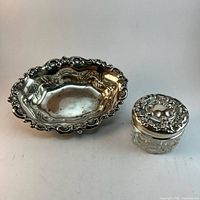 Sterling bonbon dish beside cut glass vanity jar with silver lid