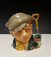 Front view of Royal Doulton The Gardener jug showing facial detail, shovel handle and vegetables