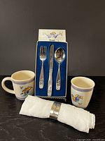 Overall lot showing mug, cup, boxed flatware, pewter napkin ring on rolled napkin