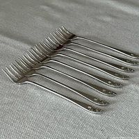 Side view of eight Birks Tudor Royal sterling silver fish forks aligned