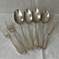 Four serving spoons, two serving forks, butter knife laid out