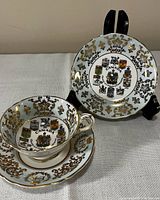 Teacup with Canada coats of arms and matching saucer beside separate saucer on stand