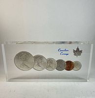 Front view of lucite block showing six embedded coins and text