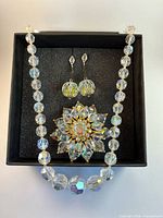 Set showing necklace, brooch and earrings in display box