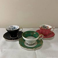 Three colour-varied teacup and saucer sets displayed side by side
