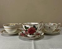 All three teacup and saucer sets side by side on table