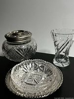 All three cut glass pieces: vanity jar with metal lid, bud vase, dish in silverplate tray