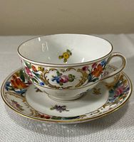 Teacup on saucer showing floral decoration and gilt detailing