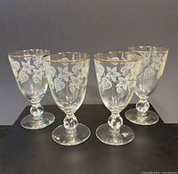 Front angled view of all four etched goblets showing pattern and gold rim