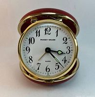 Front view of Phinney-Walker travel alarm clock in red folding case, dial visible