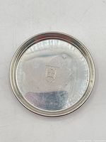 Full view of sterling silver coaster front showing crest and surface