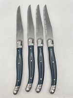 Front view of four steak knives aligned showing handles and blades