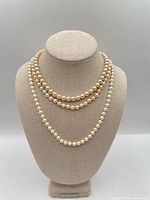 All three cream pearl necklaces draped on bust form showing relative lengths